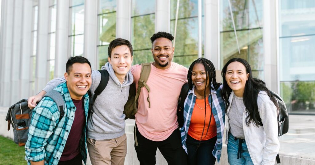 `Happy international students smiling together outside a UK university campus`