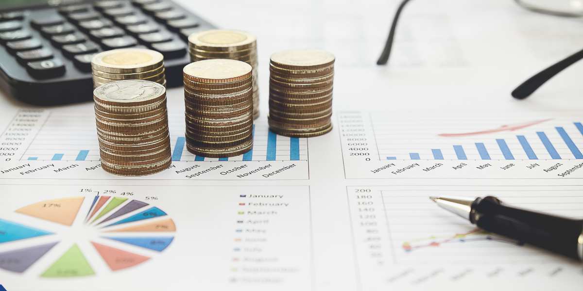 Stacks of coins placed on top of financial growth charts, graphs, and a calculator on a desk, representing budgeting and expense coverage.