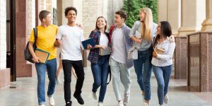 A diverse group of cheerful university students walking and talking outside a campus building, representing part-time degree opportunities for working adults in the UK.