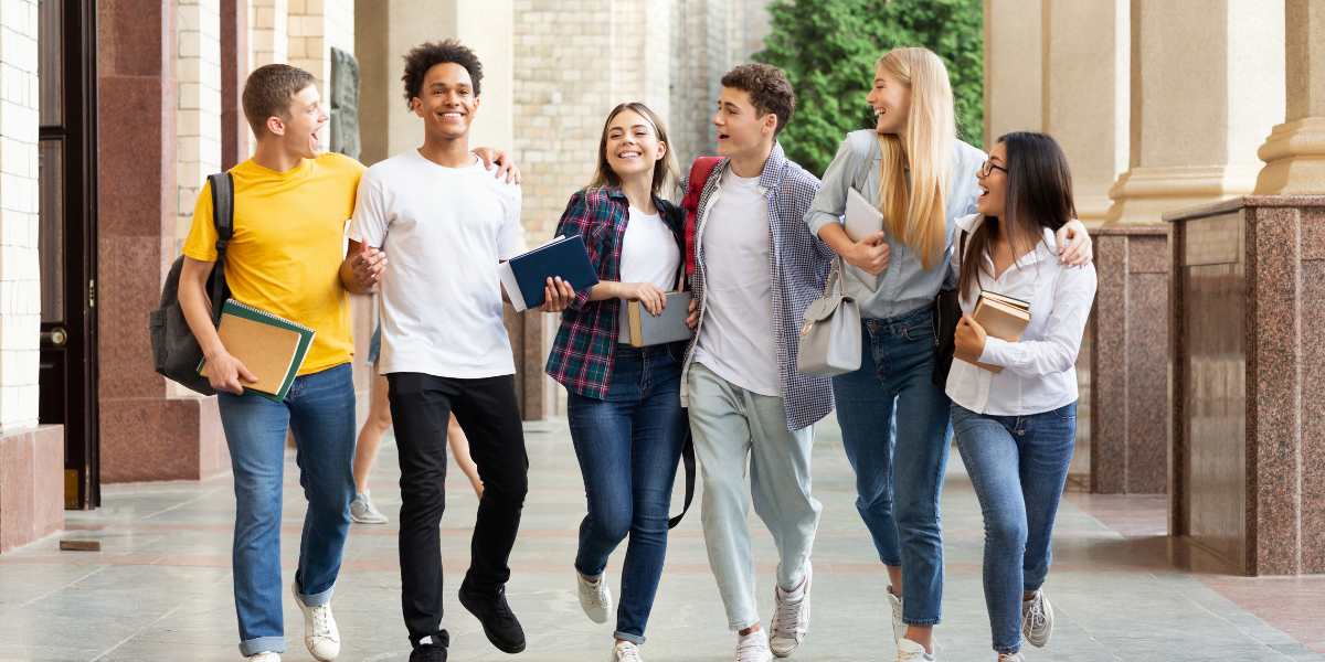 A diverse group of cheerful university students walking and talking outside a campus building, representing part-time degree opportunities for working adults in the UK.
