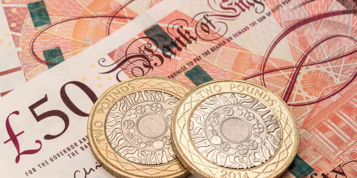Close-up of UK British currency banknotes and pound coins representing Student Loan Repayment in the UK for 2026.