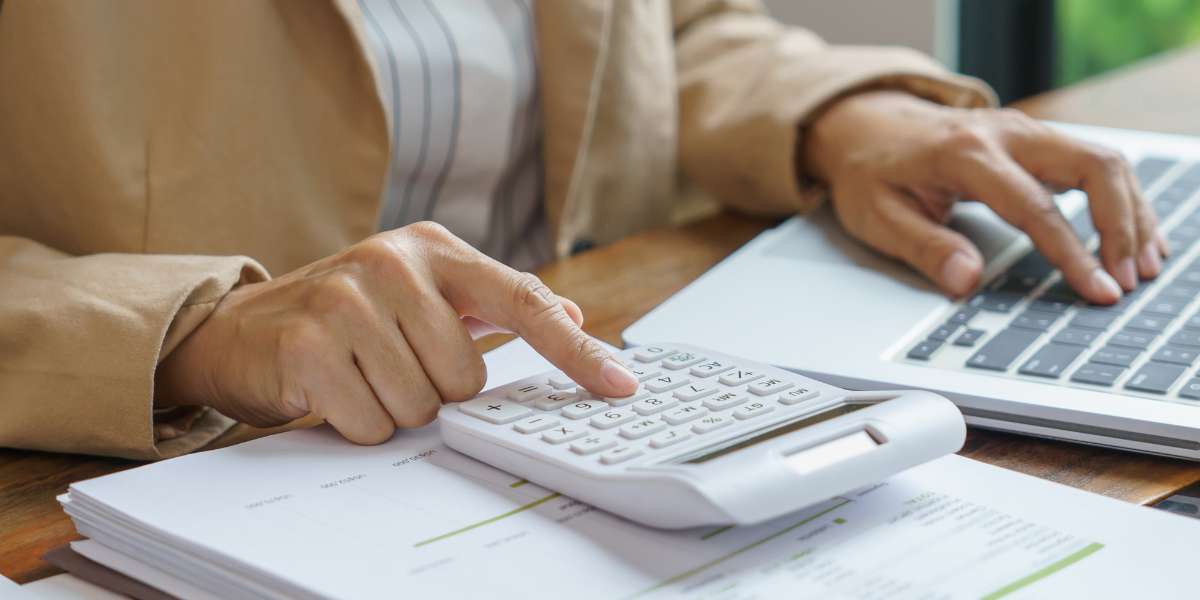 A close-up of a student or consultant using a calculator and a laptop to check home student fees eligibility, university costs, and available student funding.